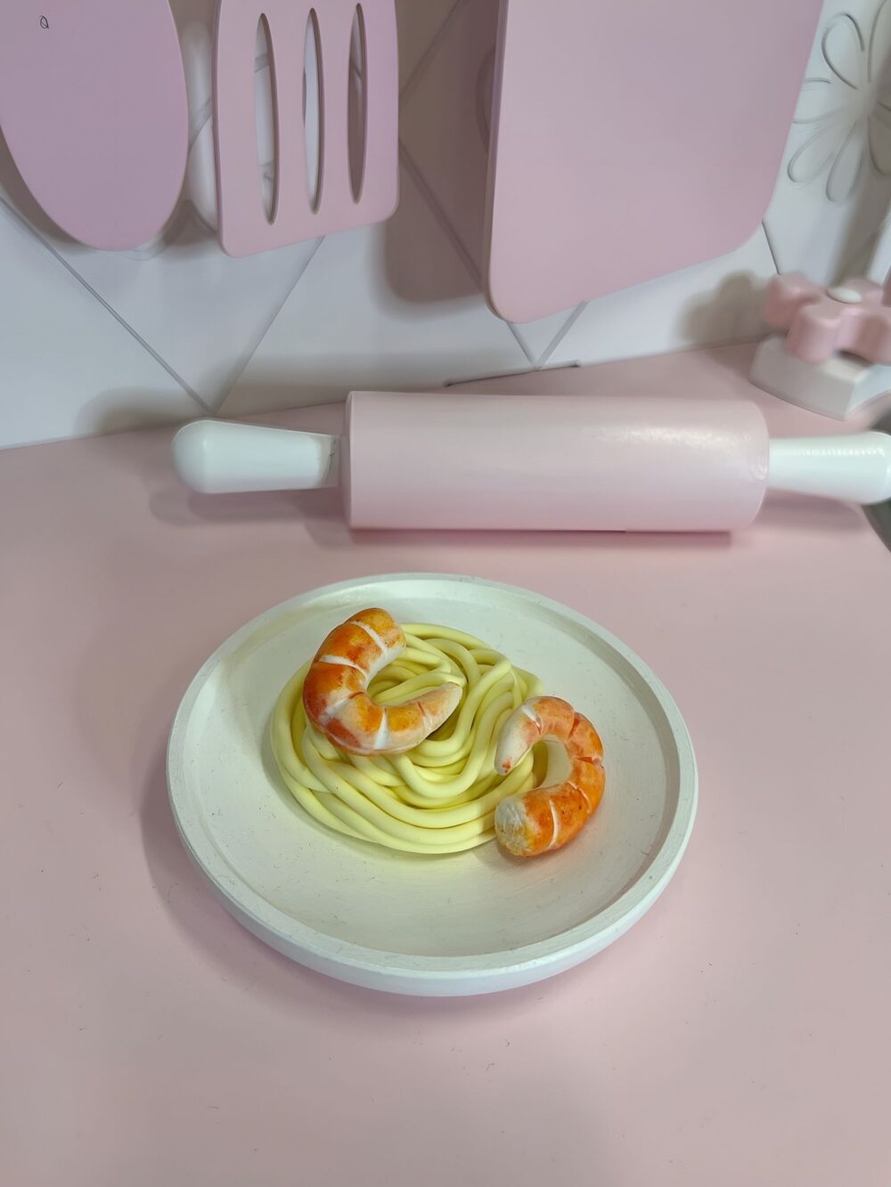 На тарелке лежит спагетти и 2 креветки из полимерной глины