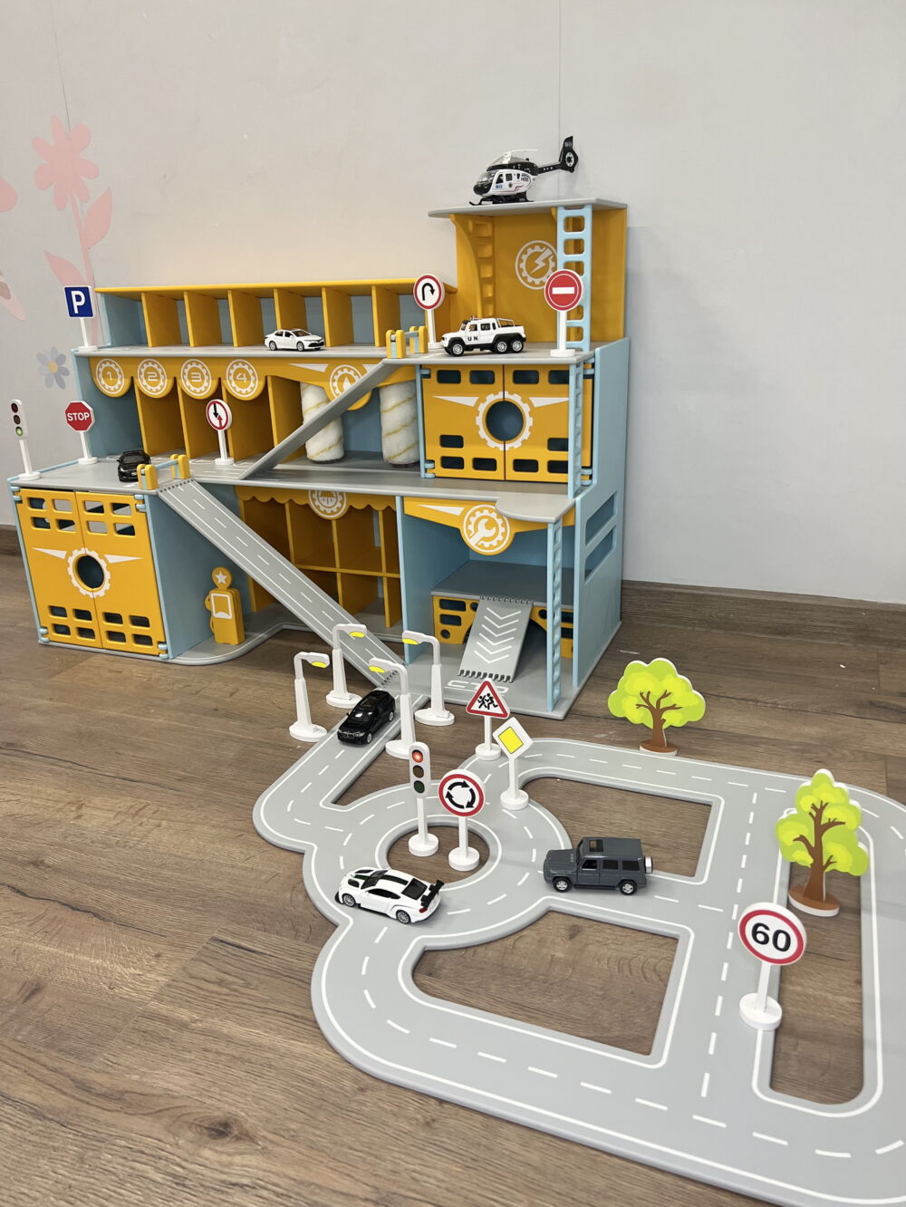 Парковка и гараж для игрушечных машинок и вертолетов со знаками дорожного движения. Исполнен в голубом и желтых цветах. Общий вид.